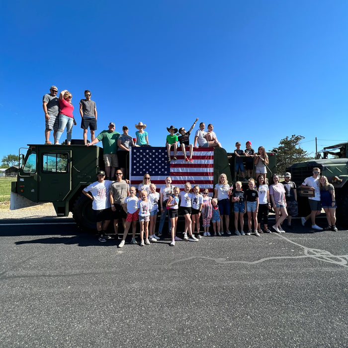 Picture of parade participants in Herriman Utah celebrating freeedom in front of large military truck